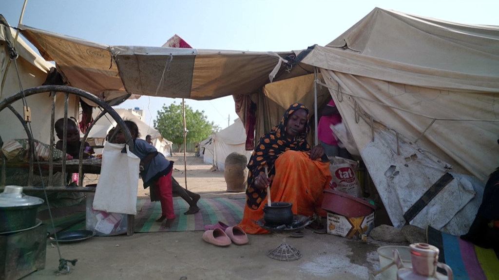 Une femme prépare un repas dans un camp de déplacés au Soudan.